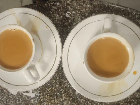 Two cups of Irani chai on saucers, seen from above.