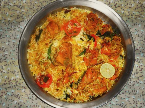 A steel pot of Hyderabadi dum biryani with a lime wedge.